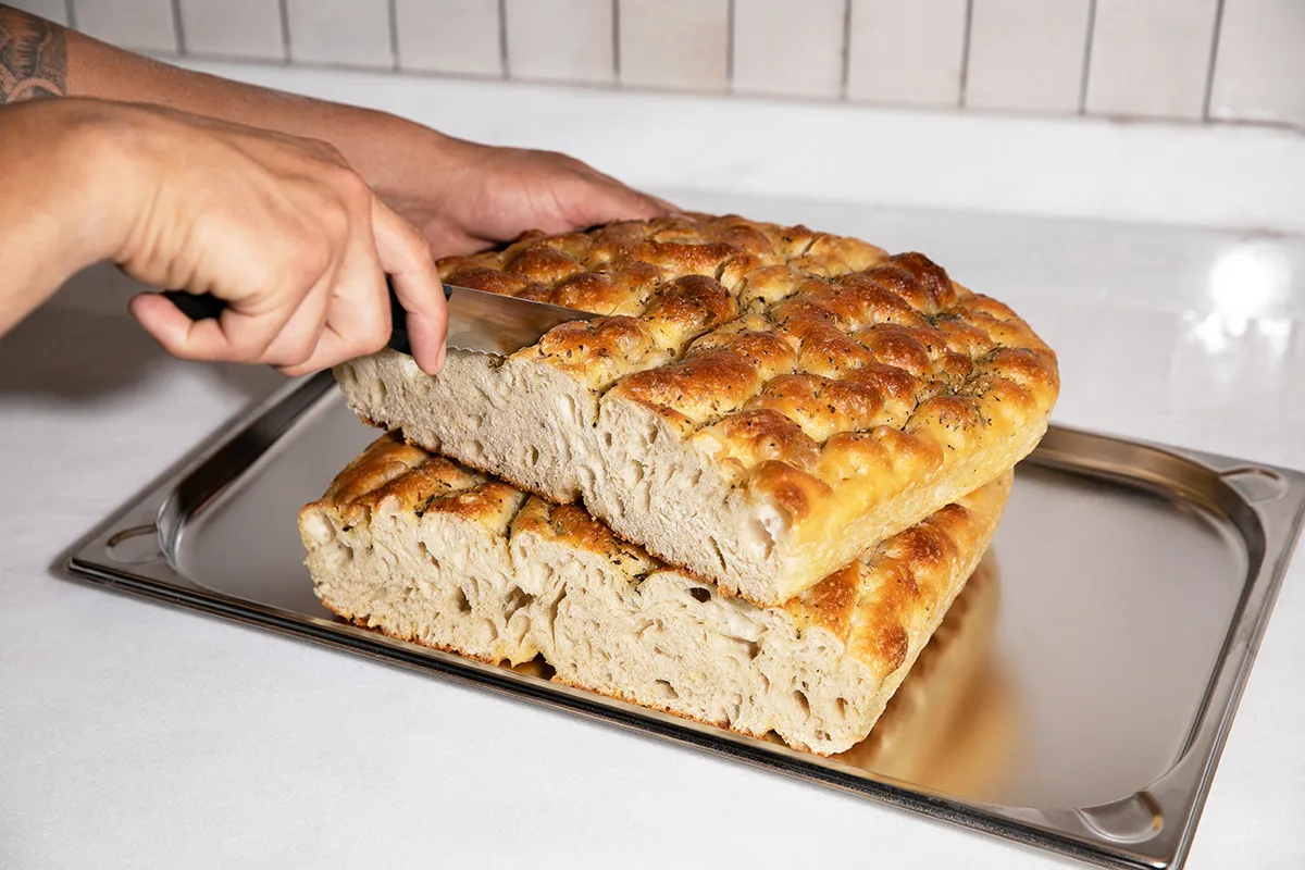 Manos cortando focaccia casera